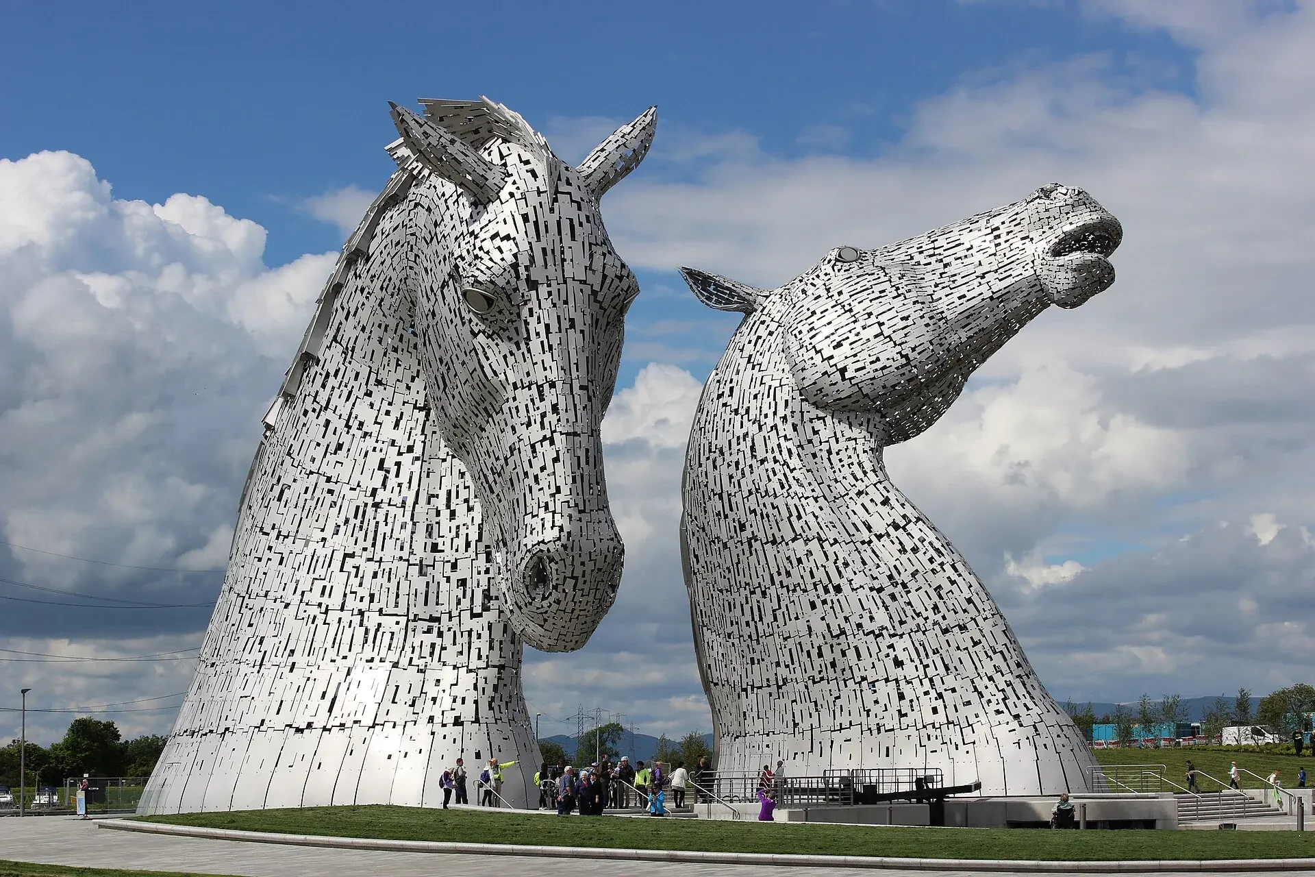 The two steel horse-head sculptures of The Kelpies at The Helix in Falkirk beneath a blue and cloudy sky