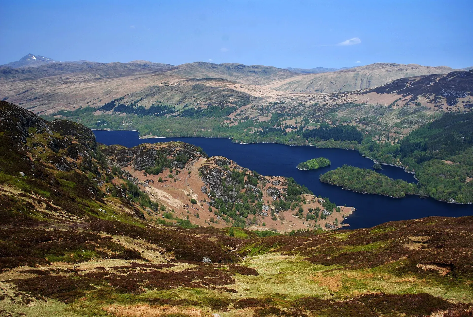 Deep-blue Loch Katrine and wooded islands beneath sunlit hills in the Trossachs