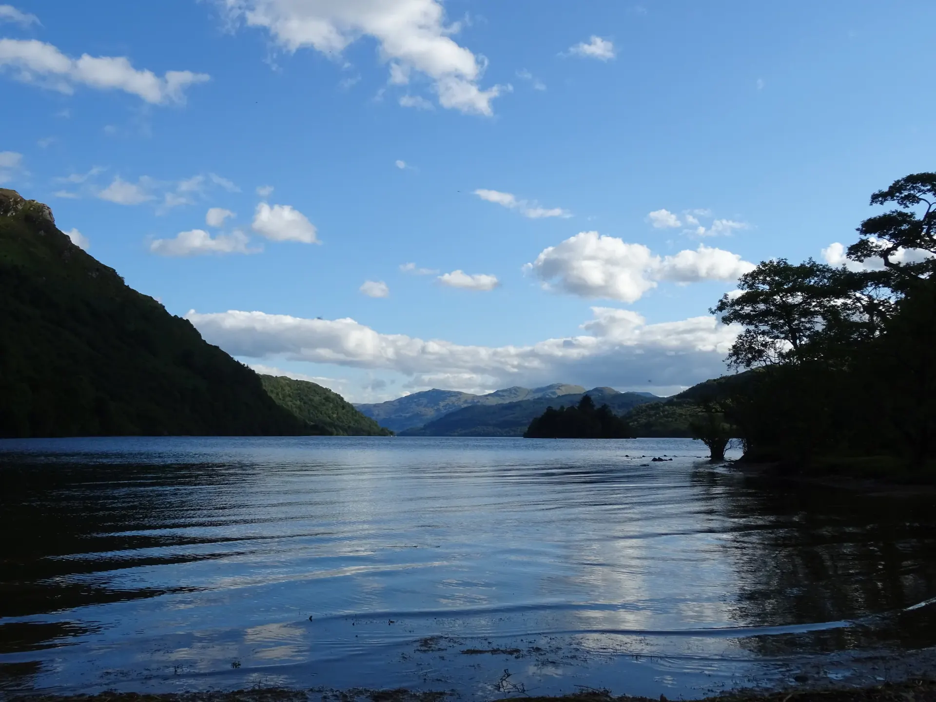 Blue water at Loch Lomond, looking towards the wooded Island I Vow and surrounding hills