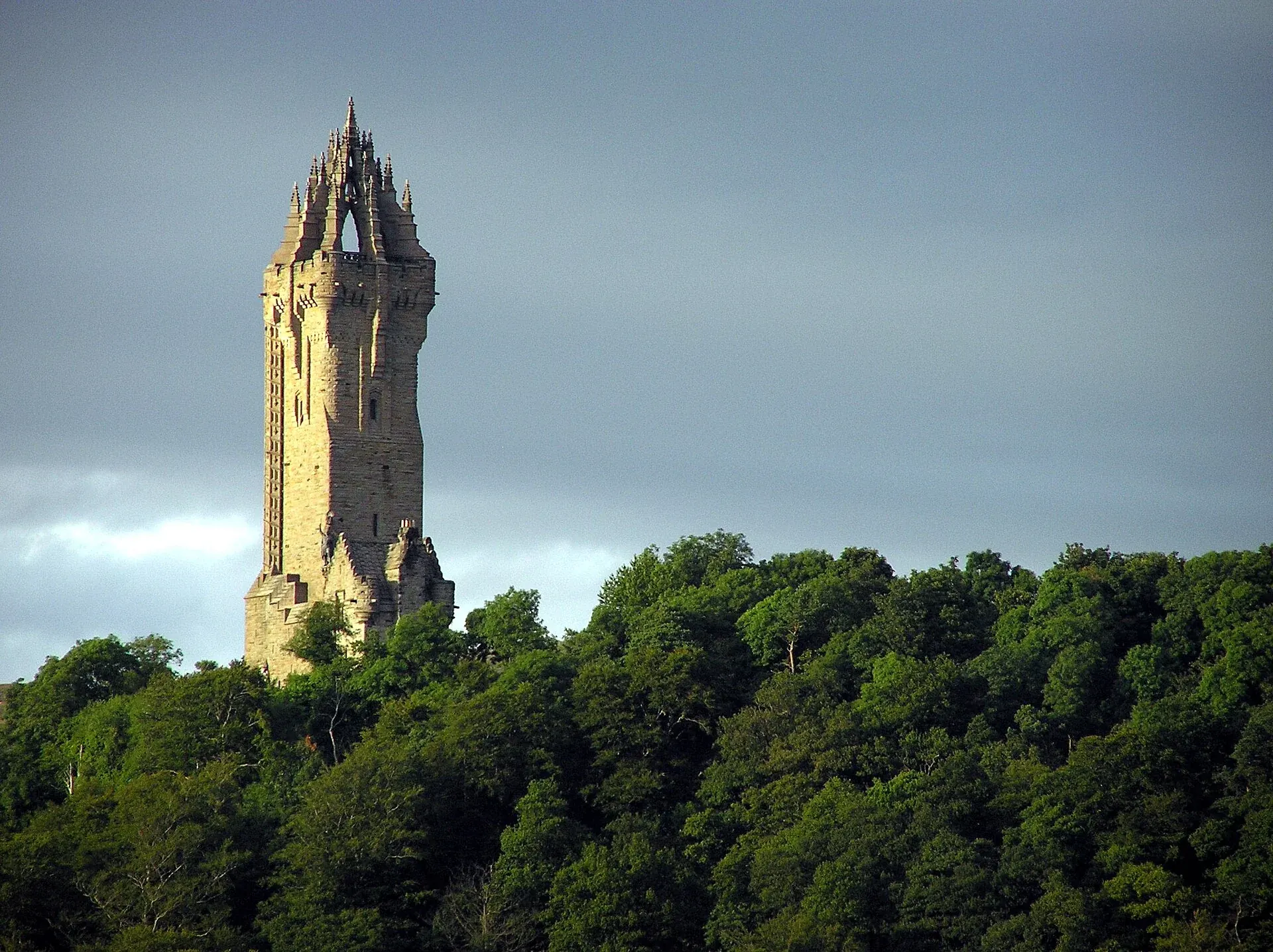 Sunlit National Wallace Monument rising above woodland on Abbey Craig near Stirling